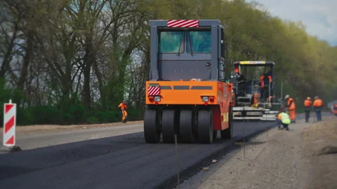 Roller machines make new asphalt roads. The asphalt paver squeezes hot asphalt. Stock Footage 130194444