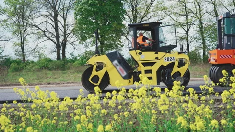 Roller machines make new asphalt roads. The asphalt paver squeezes hot asphalt. Stock Footage 130195425
