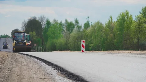 Roller machines make new asphalt roads. The asphalt paver squeezes hot asphalt. Stock Footage 130195752