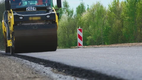 Roller machines make new asphalt roads. The asphalt paver squeezes hot asphalt. Stock Footage 130196469