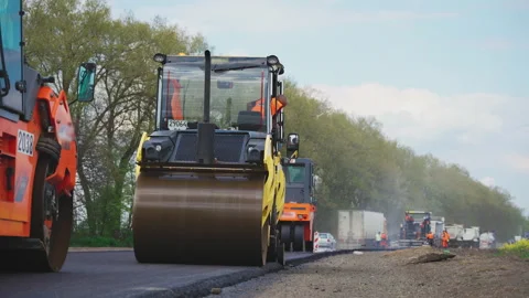 Roller machines make new asphalt roads. The asphalt paver squeezes hot asphalt. Stock Footage 130196551