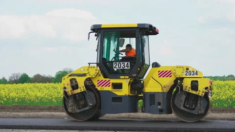Roller machines make new asphalt roads. The asphalt paver squeezes hot asphalt. Stock Footage 130198058