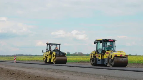 Roller machines make new asphalt roads. The asphalt paver squeezes hot asphalt. Stock Footage 130198061