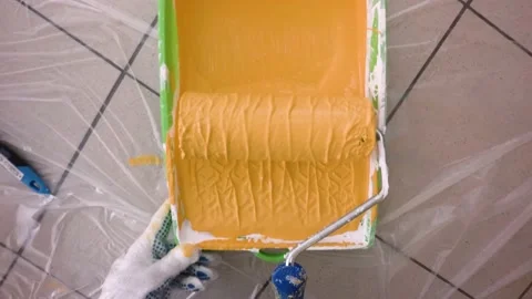 Roller in orange paint and continues painting the wall. Stock Footage 141080746