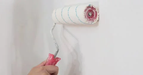 Roller painting white wall with white paint in the frame and leaves the frame 库存影片 131817218