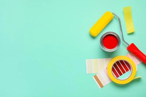 Roller with palette samples, can of paint and adhesive tape roll on turquoise Stock-Fotos