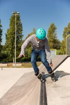 A roller skater does a trick on a ramp at a skate park Stock Photos