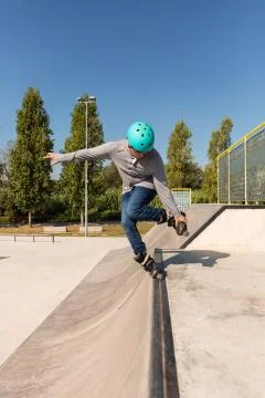 A roller skater does a trick on a ramp at a skate park Stock Photos