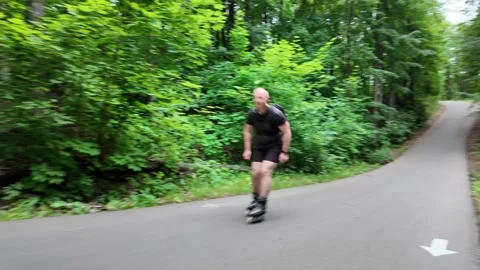 Roller skater speeds down mountain and climbs steep path in forest Video stock 338307011