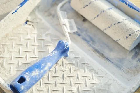 Roller in white paint in a container Stock Photos
