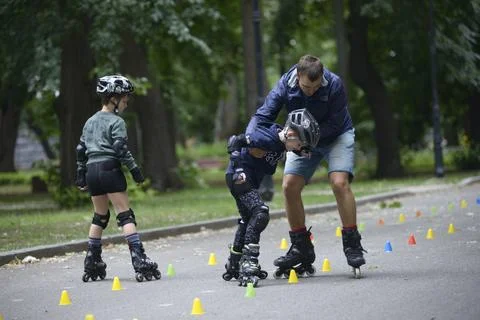 Rollerblading. Trainer correcting boy movements teaching of artistic slalom.. Stock Photos