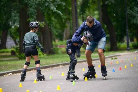 Rollerblading. Trainer corrects boy movements teaching of artistic slalom Stock Photos