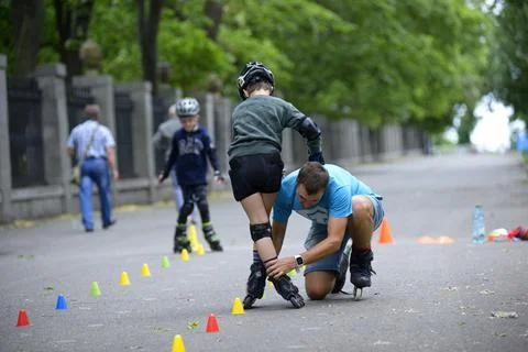Rollerblading. Trainer corrects movements of boys legs teaching of artistic s Stock Photos