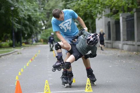 Rollerblading. Trainer messing around with little boy during teaching him of Stock Photos