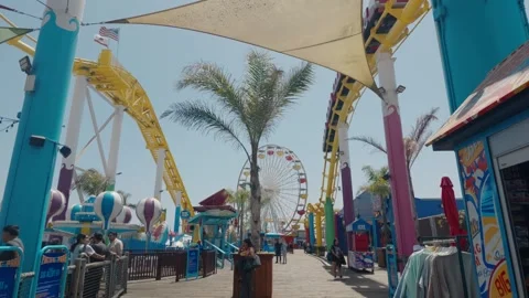 Rollercoaster rides into wide shot of Santa Monica Pier amusement park Stock Footage 341883964