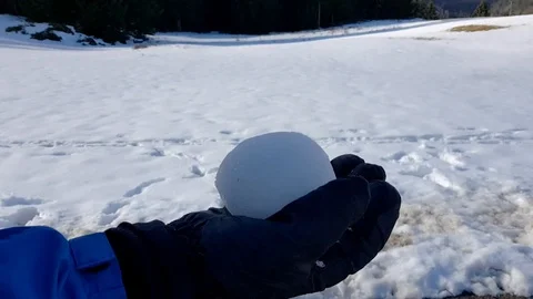 Rolling big snowball in gloved hand and throwing it up in the air in the Stock Footage 97890567