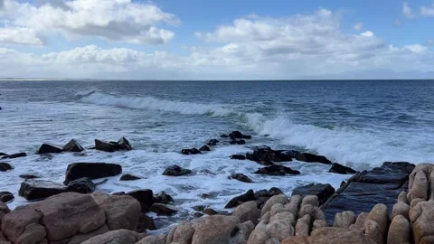 Rolling blue waves washing over the rocks and boulders Stock Footage 283744406