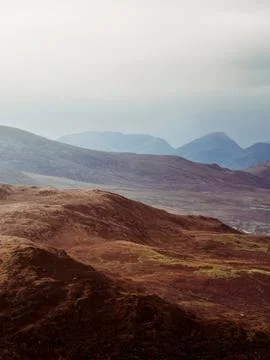 Rolling brown hills covered in sparse vegetation dominate the foreground. 스톡 사진