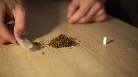 Rolling cigarette by using blended tobacco paper and filter on close up Stock Footage 129448665