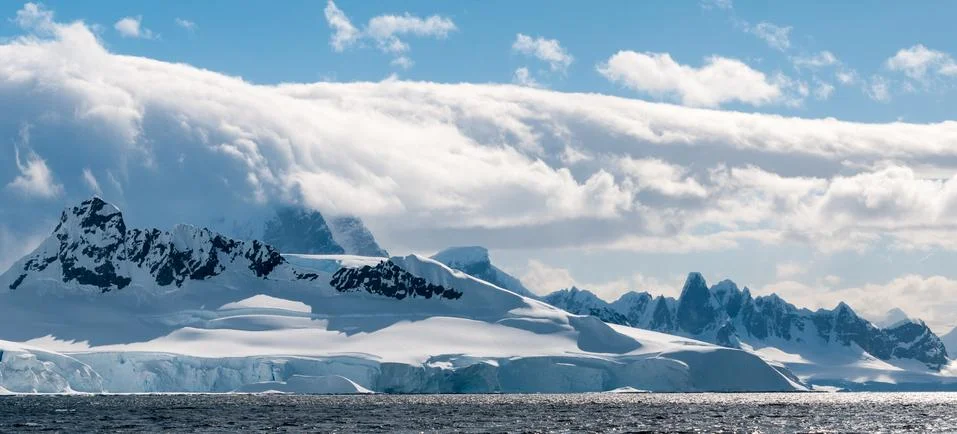 Rolling clouds over snow-capped mountains and ice cliffs, Antarctica Stock Photos