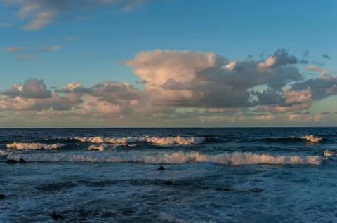 Rolling cloudscape over seawaves at sunset Stock Photos
