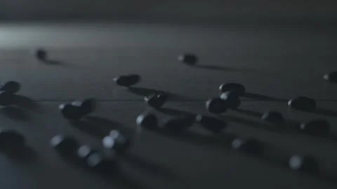 Rolling coffee beans on the table. Slow motion dark theme. Stock Footage 130858818
