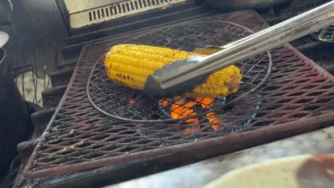 Rolling corn in sauce and placing back over flaming grill, Japan Stock-Footage 343077018