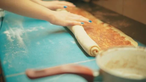 Rolling dough into a cinnamon log, close up of teenager shaping homemade buns. Video stock 332751937