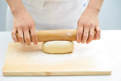 Rolling the dough with a rolling pin, bread making process Stock Photos