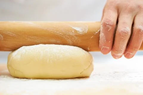 Rolling the dough with a rolling pin, bread making process Stock Photos