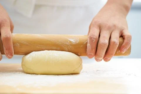 Rolling the dough with a rolling pin, bread making process Stock Photos