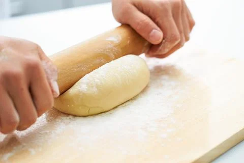 Rolling the dough with a rolling pin, bread making process Stock Photos