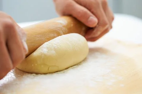 Rolling the dough with a rolling pin, bread making process Stock Photos