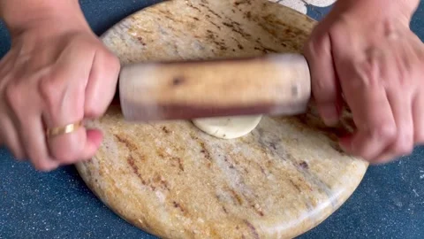 Rolling a dough of whole wheat flour into circles to make a tea time snack .. Stock Footage 338373632
