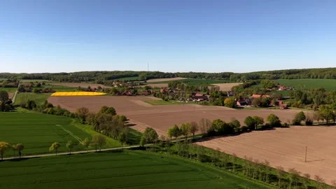 Rolling farmland and patchwork fields with small European village and tree Video stock 334671846
