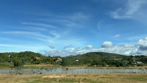 Rolling fields and distant hills pass by under a wide blue sky with drifting Stock Footage 325381637