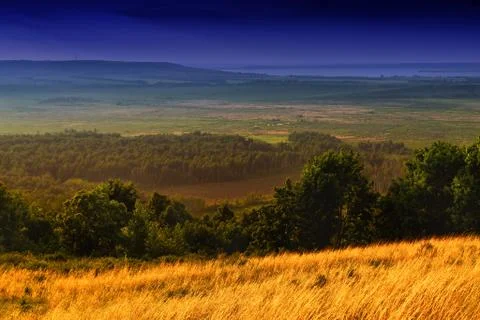 Rolling fields of hay with a strong blue sky and sweeping hills Stock Photos