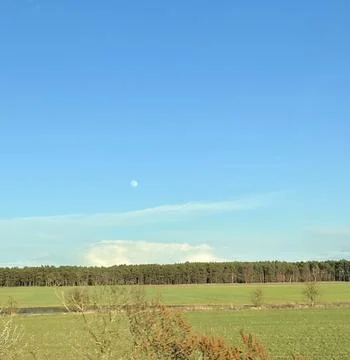 Rolling Fields Under a Blue Sky with the Moon Stock Photos