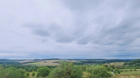 Rolling Green Countryside Beneath Layered Cloudy Sky Stock Footage 345650708