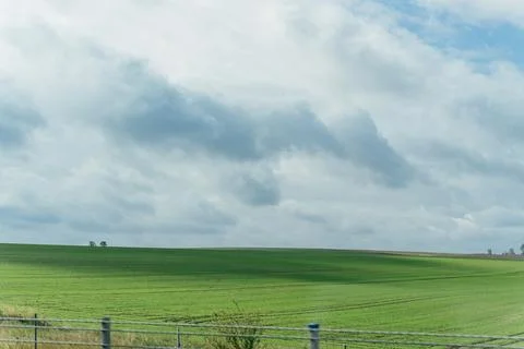 Rolling Green Fields Under Cloudy Sky Stock Photos
