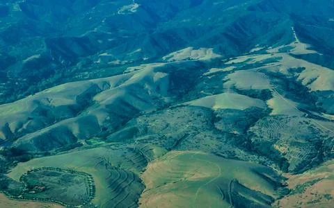 Rolling Green Hills and Distant Blue Mountains Aerial View Agricultural Ter.. Stock Photos
