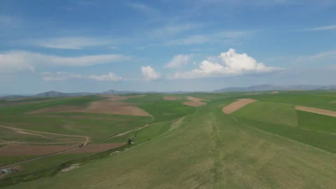 Rolling green hills and fields under a vast sky with white clouds. Stock Footage 334545920