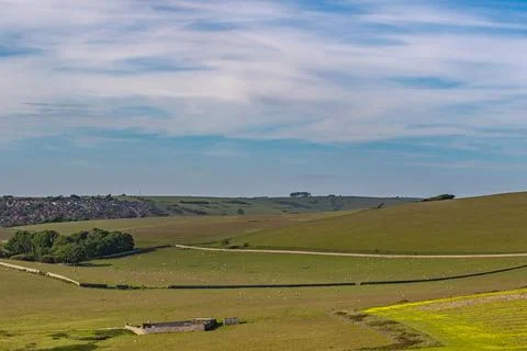 Rolling green hills with patchwork fields under a blue sky with wispy cloud.. 写真素材