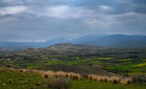 Rolling green hills under a dramatic sky at dusk near a peaceful valley Stock Photos
