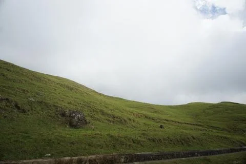 Rolling green hills under a dramatic cloudy sky 写真素材