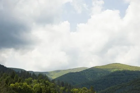 Rolling Green Mountains under Cloudy Sky with Lush Forest 스톡 사진
