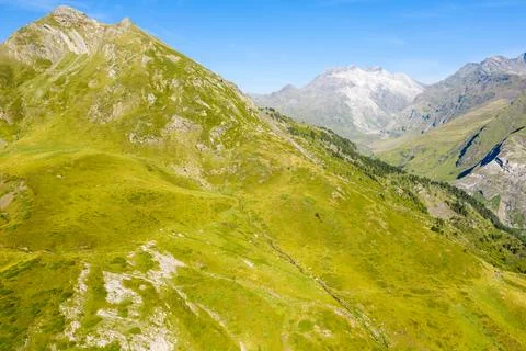 Rolling green slopes and distant snowy peaks Stock Photos