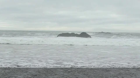 Rolling grey waves break on wide beach on windy day Stock Footage 73337994