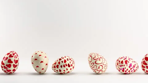 Rolling Heart-Patterned Eggs on White Background. Looped animation Stock Footage 300763485