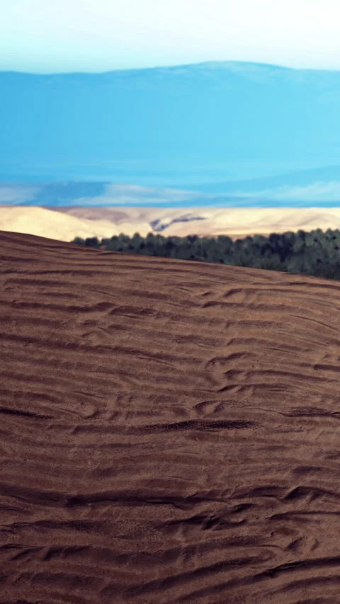 Rolling hills and fields with patterns near a distant mountain range at dusk Stock Footage 334294273